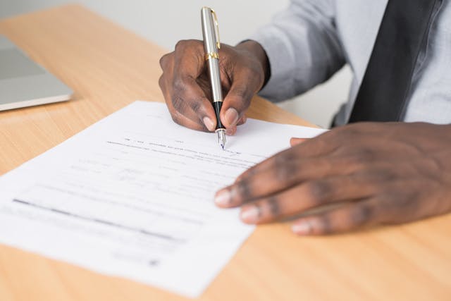 Person using a pen to sign a document